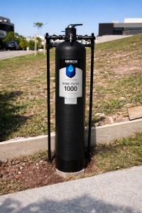 Filtro central preto American Home Filter 1000 instalado em área externa residencial